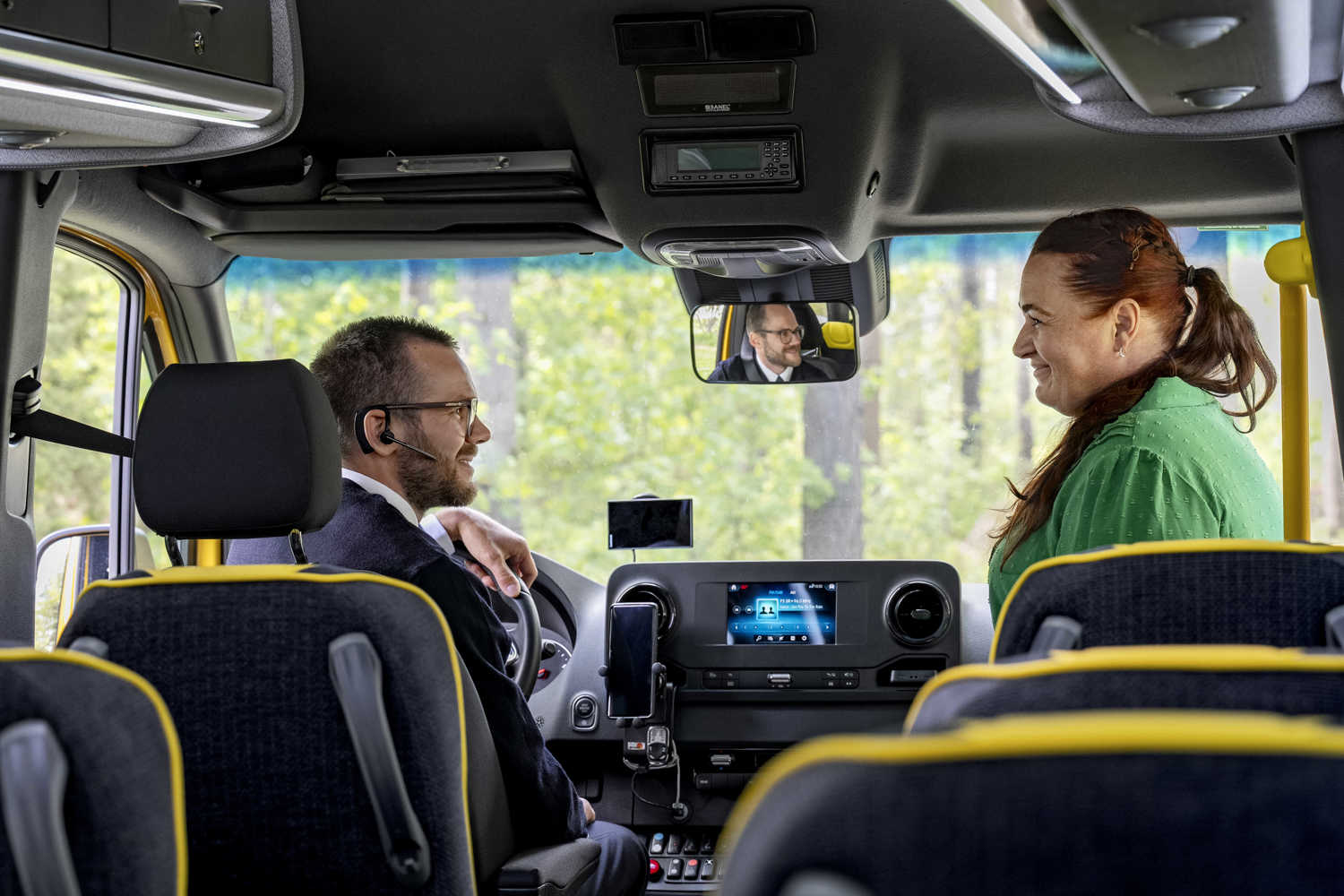 Busschaufför med resenär som är på väg in i bussen. 