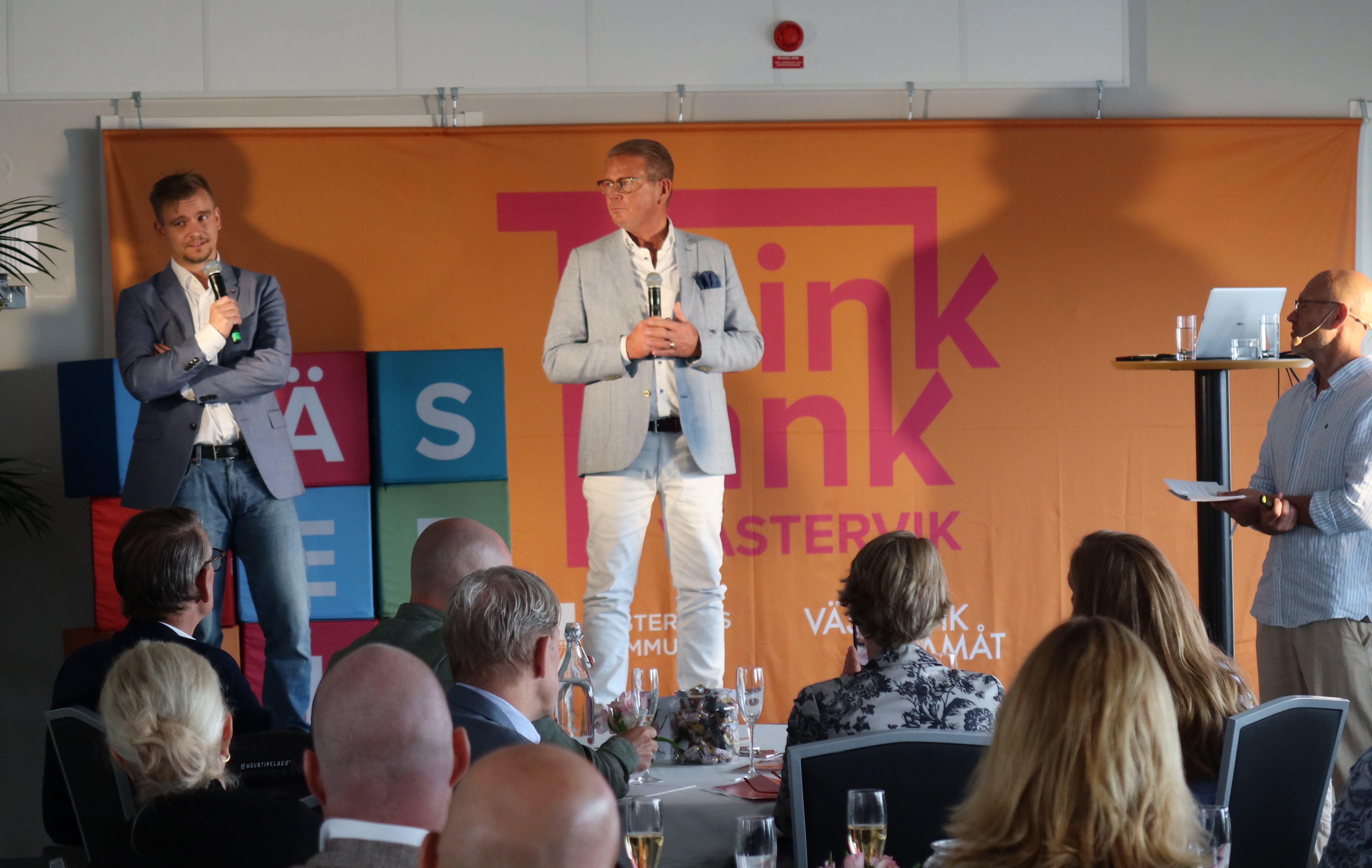 Två män på en scen med publik framför.  