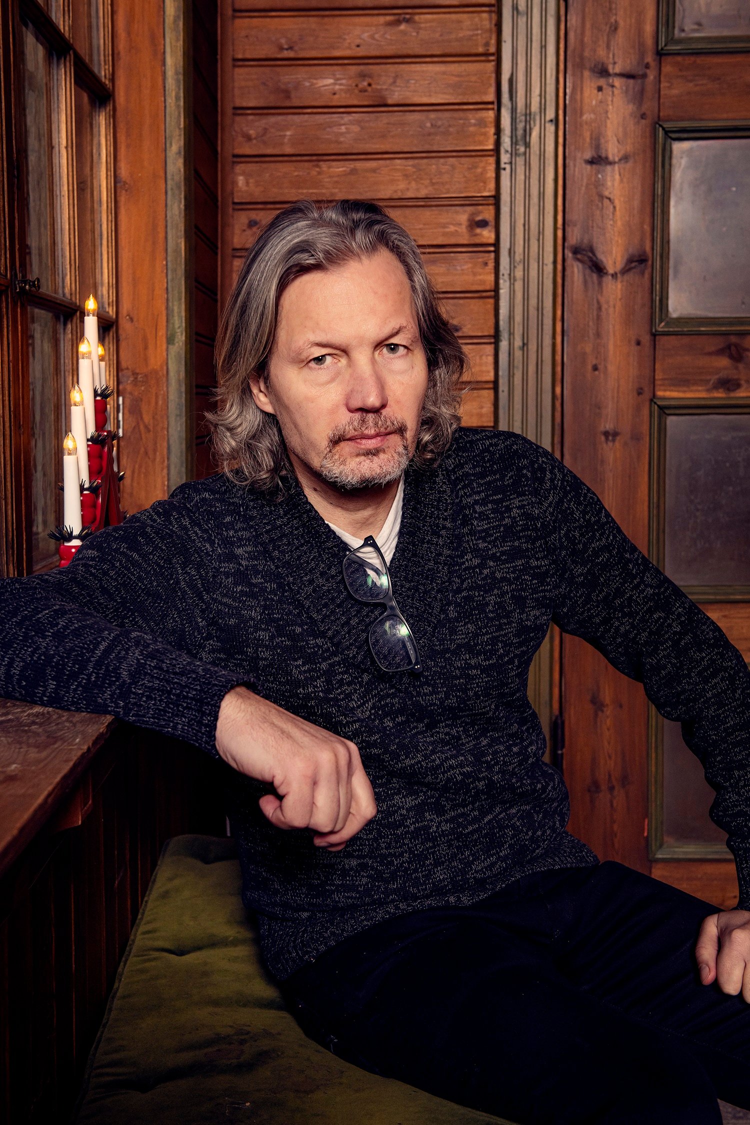 Porträttbild av Kalle Åström i mörka kläder och glasögon hängande i halsringningen. 