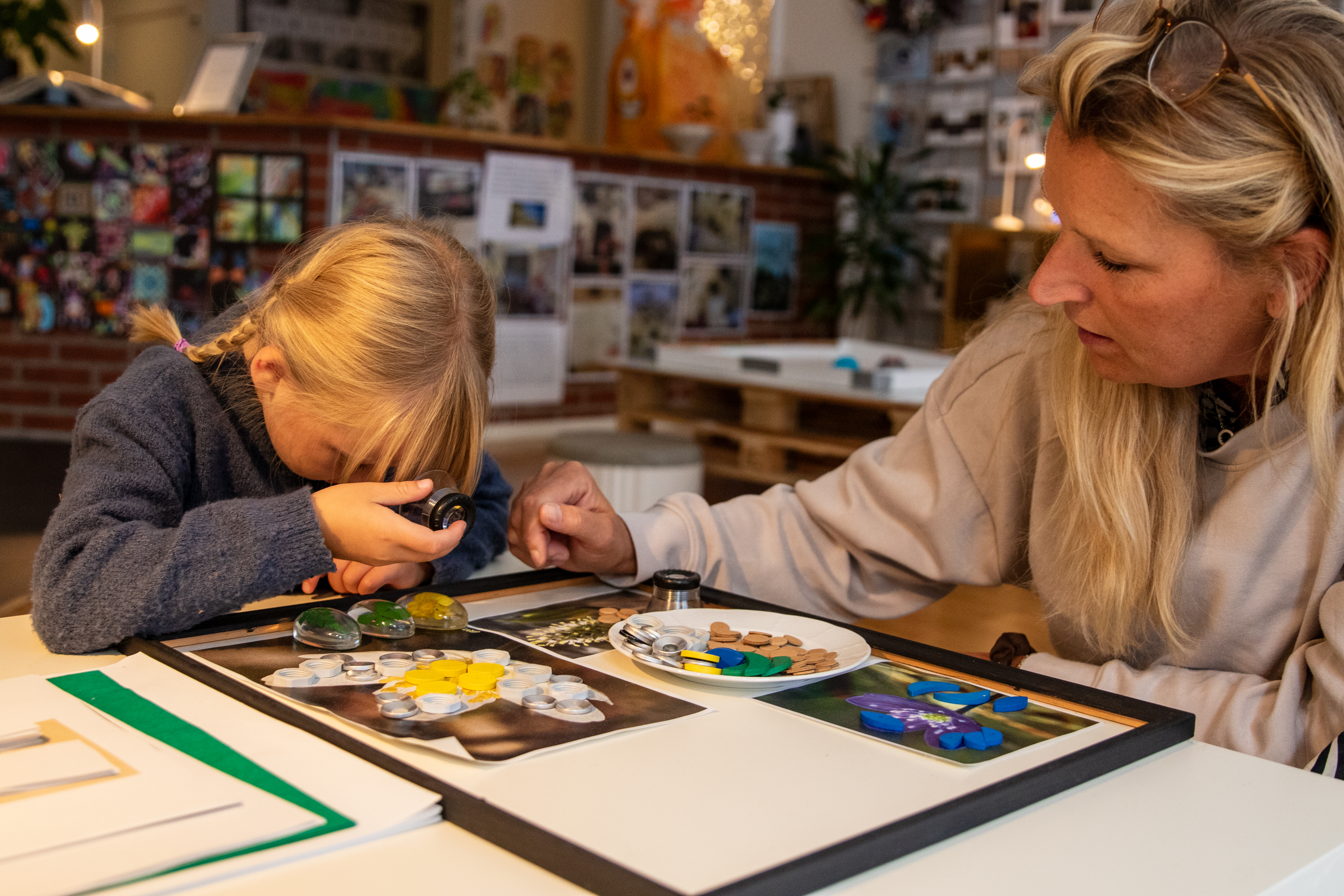 Ateljerista leker med barn som kollar i förstorinsglas.