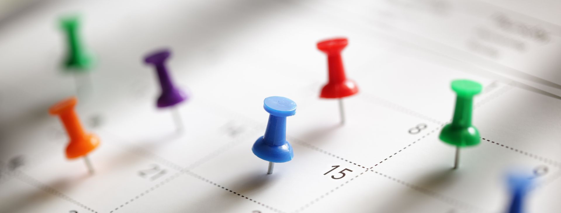 Knappnålar vid en kalender för att markera viktiga datum.