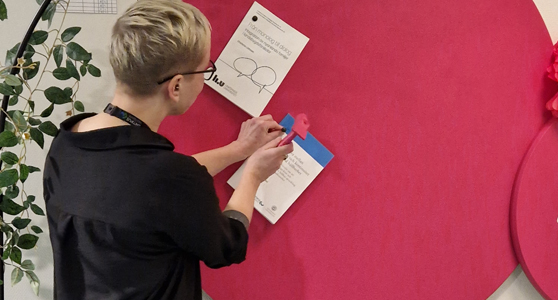 Bilden föreställer doktoranden Caroline Ärleskog som spikar upp sin avhandling på väggen.