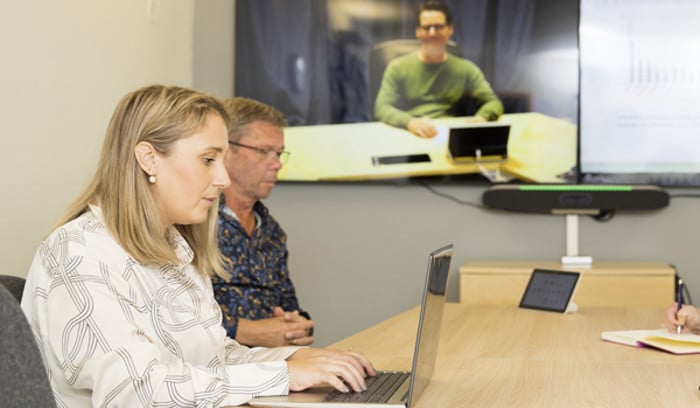 Flera personer som sitter i hybridmöte.