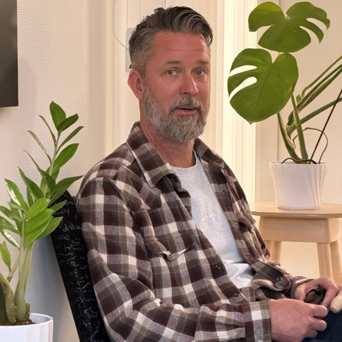 En man i en fåtölj med blommor omkring.