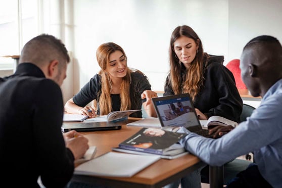 En grupp  studenter som sitter vid ett bord. 