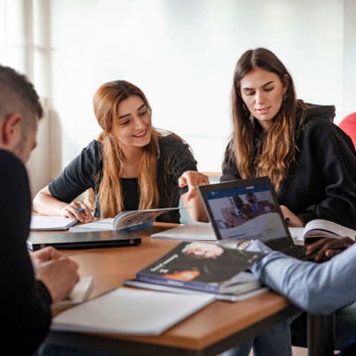 En grupp  studenter som sitter vid ett bord. 