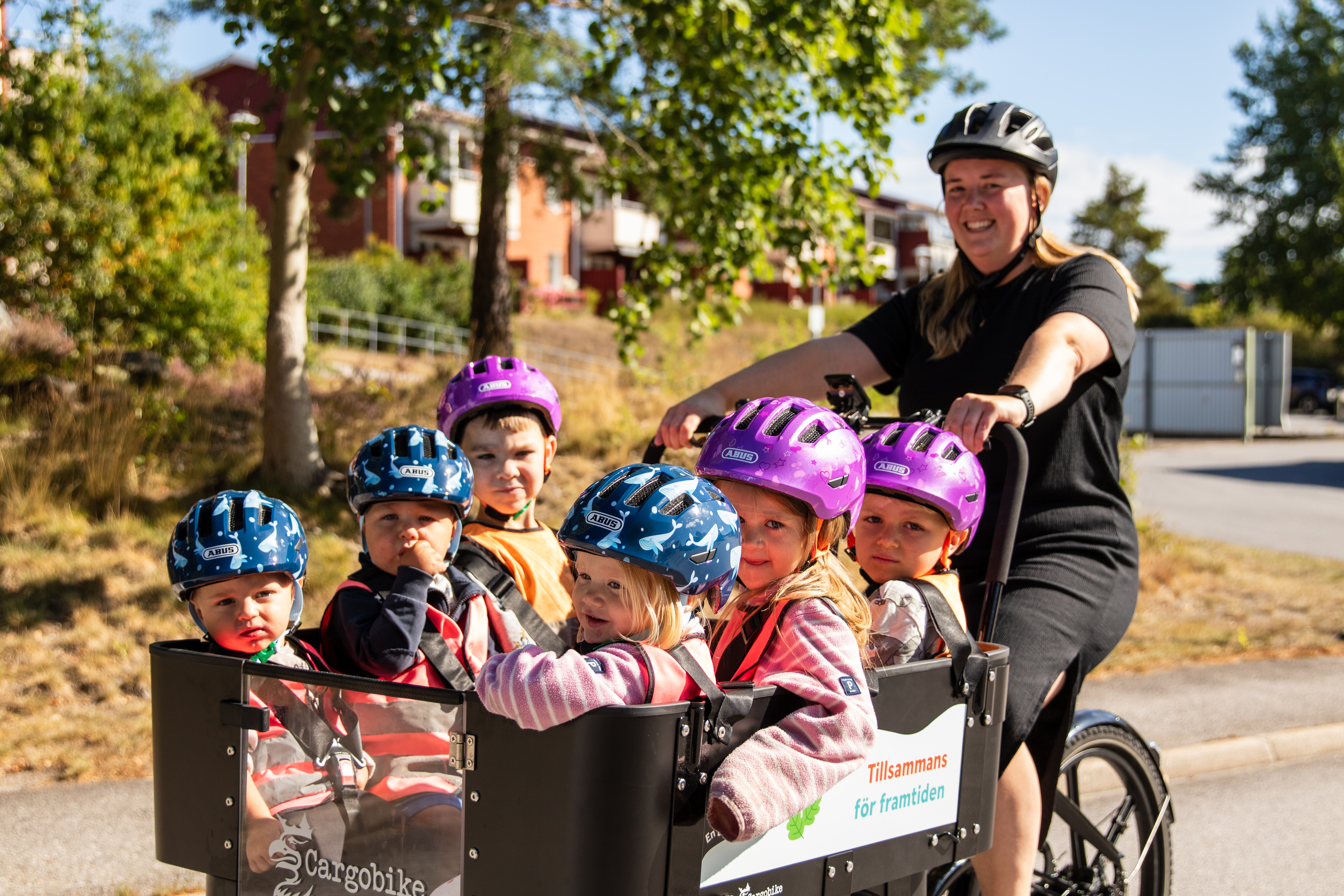 Lovisa som cyklar med barnen i lådcykel.