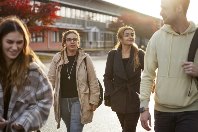 fyra unga personer går utomhus mot en kamera