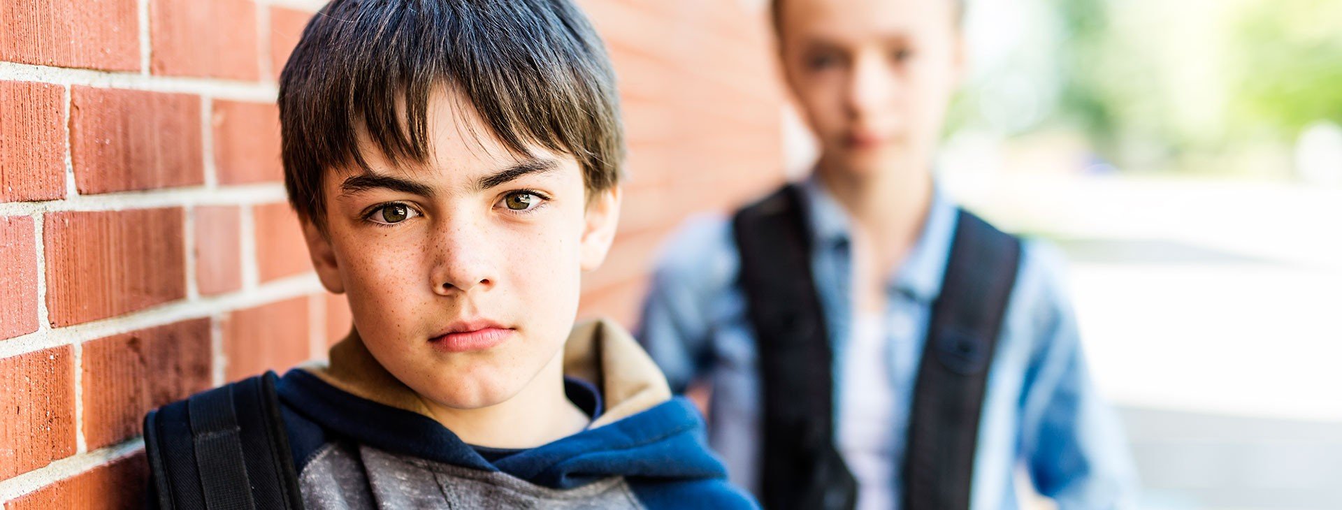 En allvarlig pojke i förgrunden och en flicka som står bakom honom