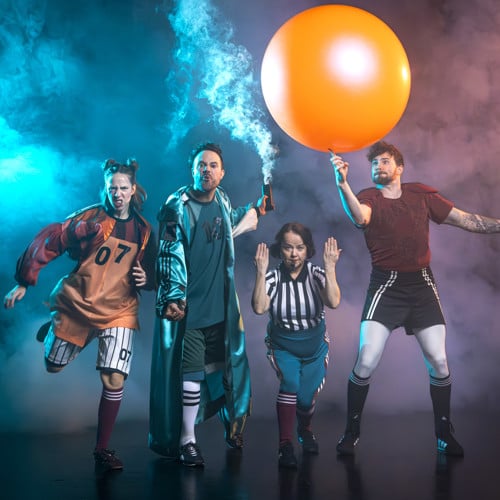 Hela ensemblen står med en stor fotboll och ler mot alla. 