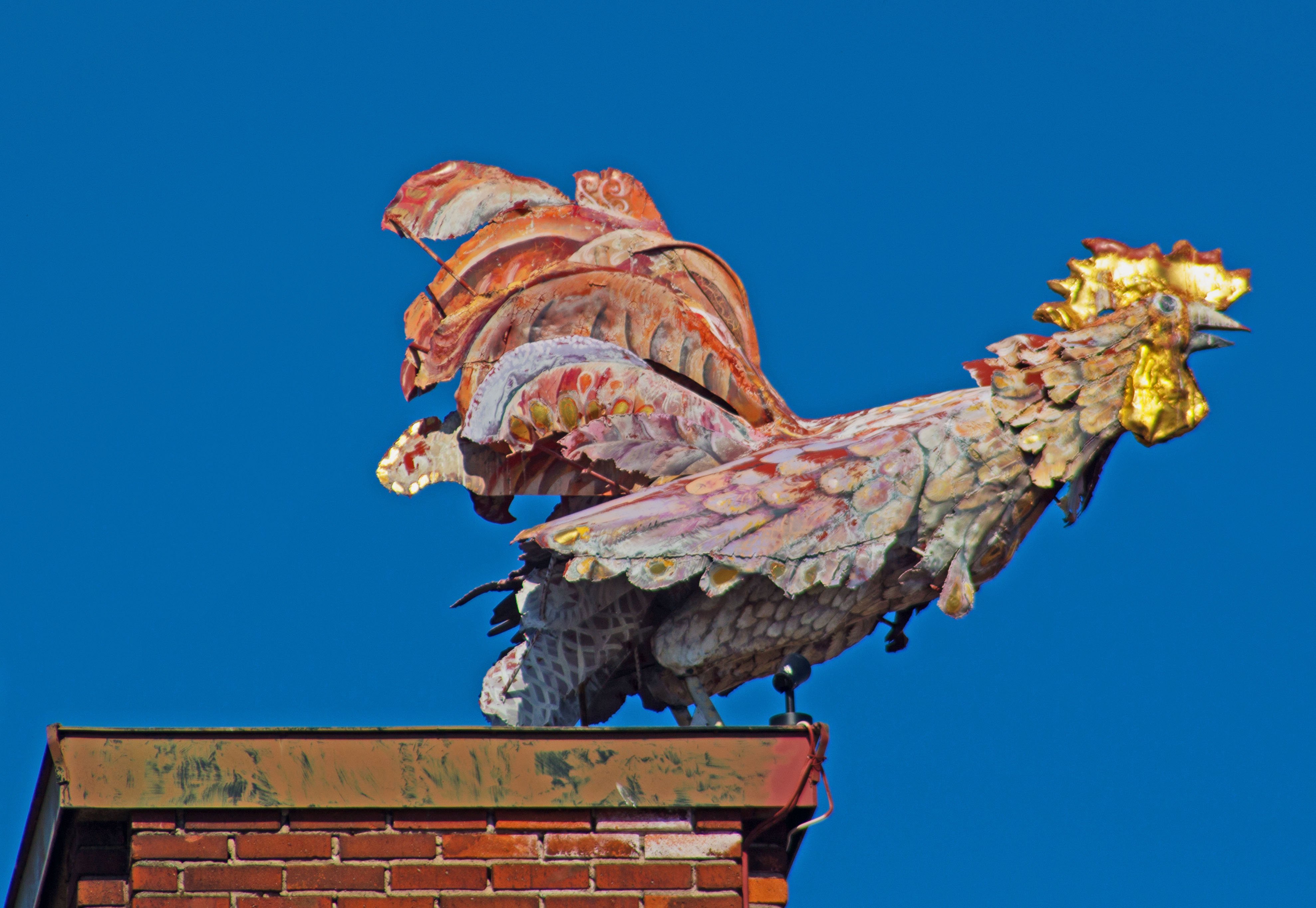 Bildtolkning: En bild av tuppen som sitter på taket på ett av husen på bostadsområdet Midgård.