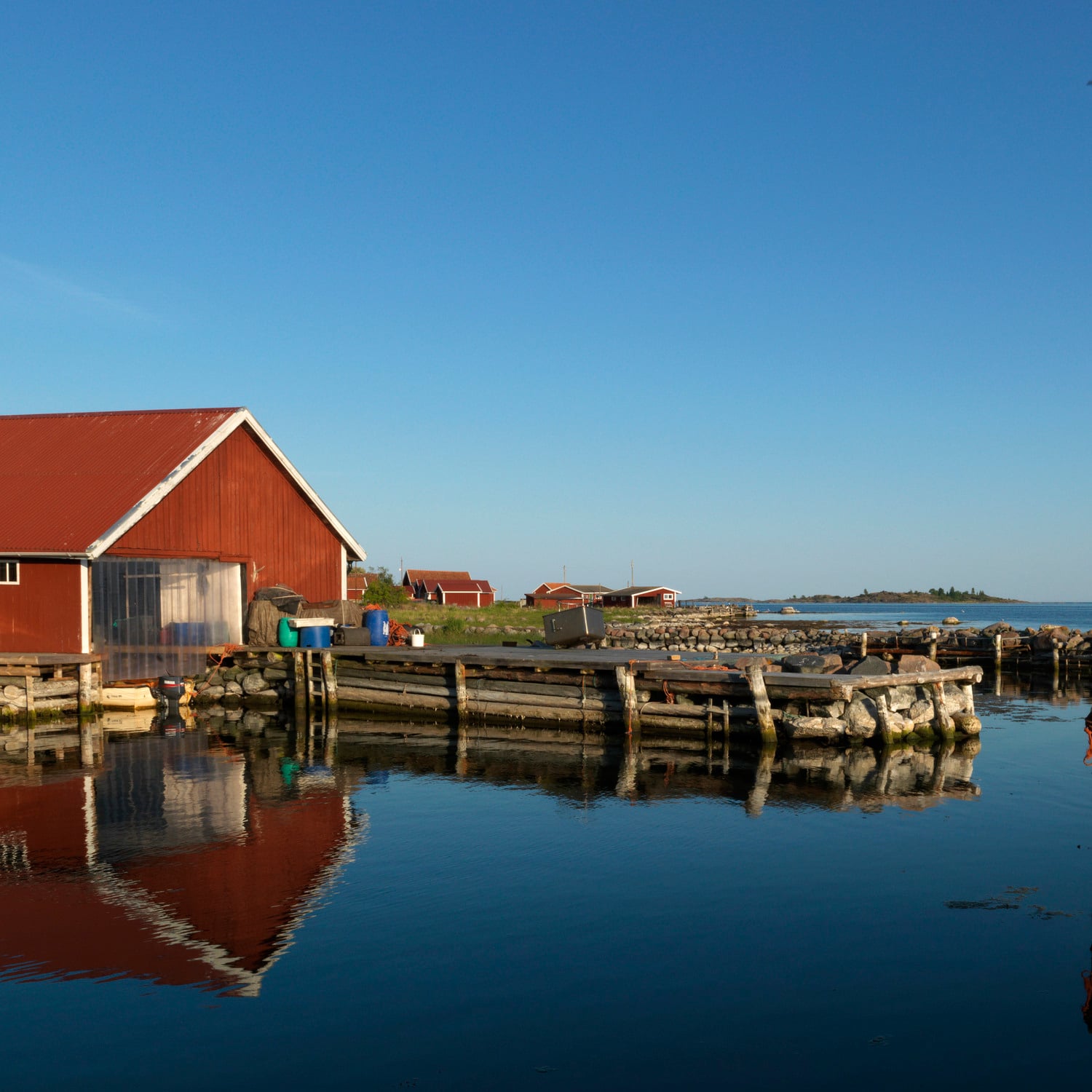 Båthus och en brygga tillsammans spegelblankt hav