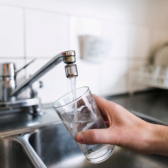 bild på glas som fylls på med vatten ur en kökskran