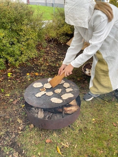 Elev som steker bröd på gammeldags vis.