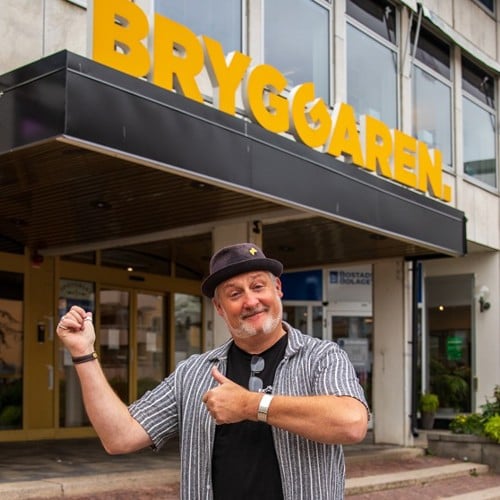 Tobias utanför Bryggaren som pekar på Bryggarens gula skylt.