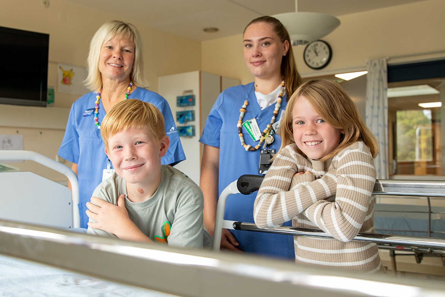 Två elever ler och är glada tillsammans med sjukvårdspersonal.