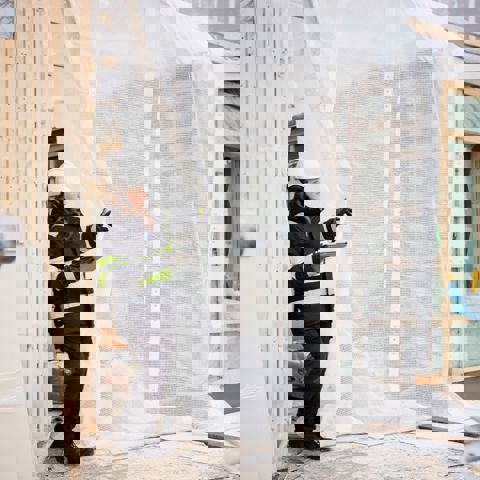 Kvinna på byggarbetsplats som står med en ritning och pekar.