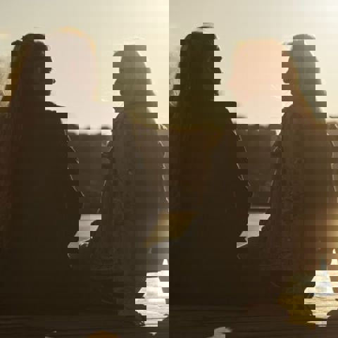 Kvinnor pratar i motljus på en brygga.