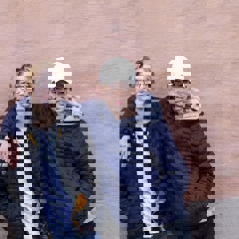 Tjej- och killkompis mot rosa vägg.