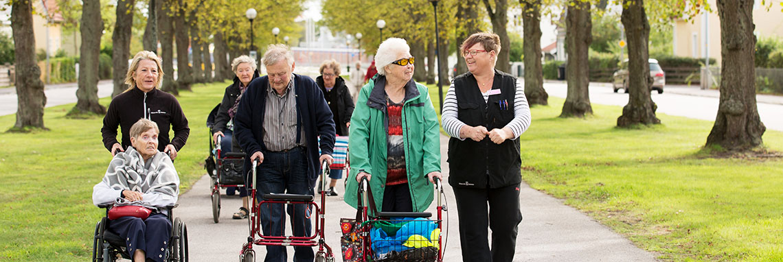 Vårdpersonal ute på promenad med äldre personer