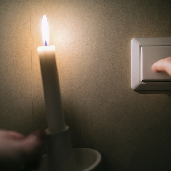 bild på en hand som håller ett levande ljus vid en lampknapp