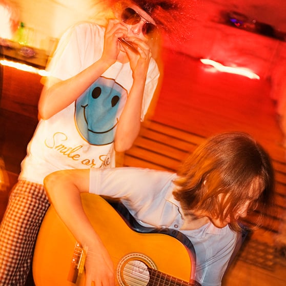 Bild på två unga musiker som spelar munspel och gitarr