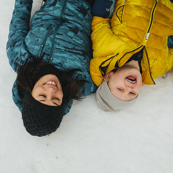 Barn och mamma som skrattar i snön