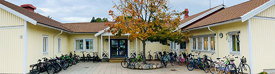 Fasaden till Näktergalens skola med ett gult hus och parkerade cyklar